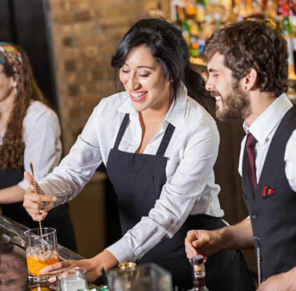 Un nouvel employé heureux apprend à préparer des boissons mixtes dans un bar